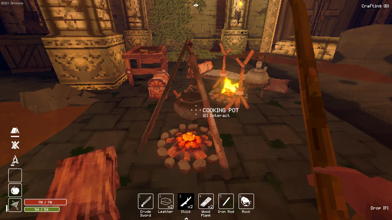 First-person view of a dungeon camp with a cooking pot, fire, tools, and crafting inventory