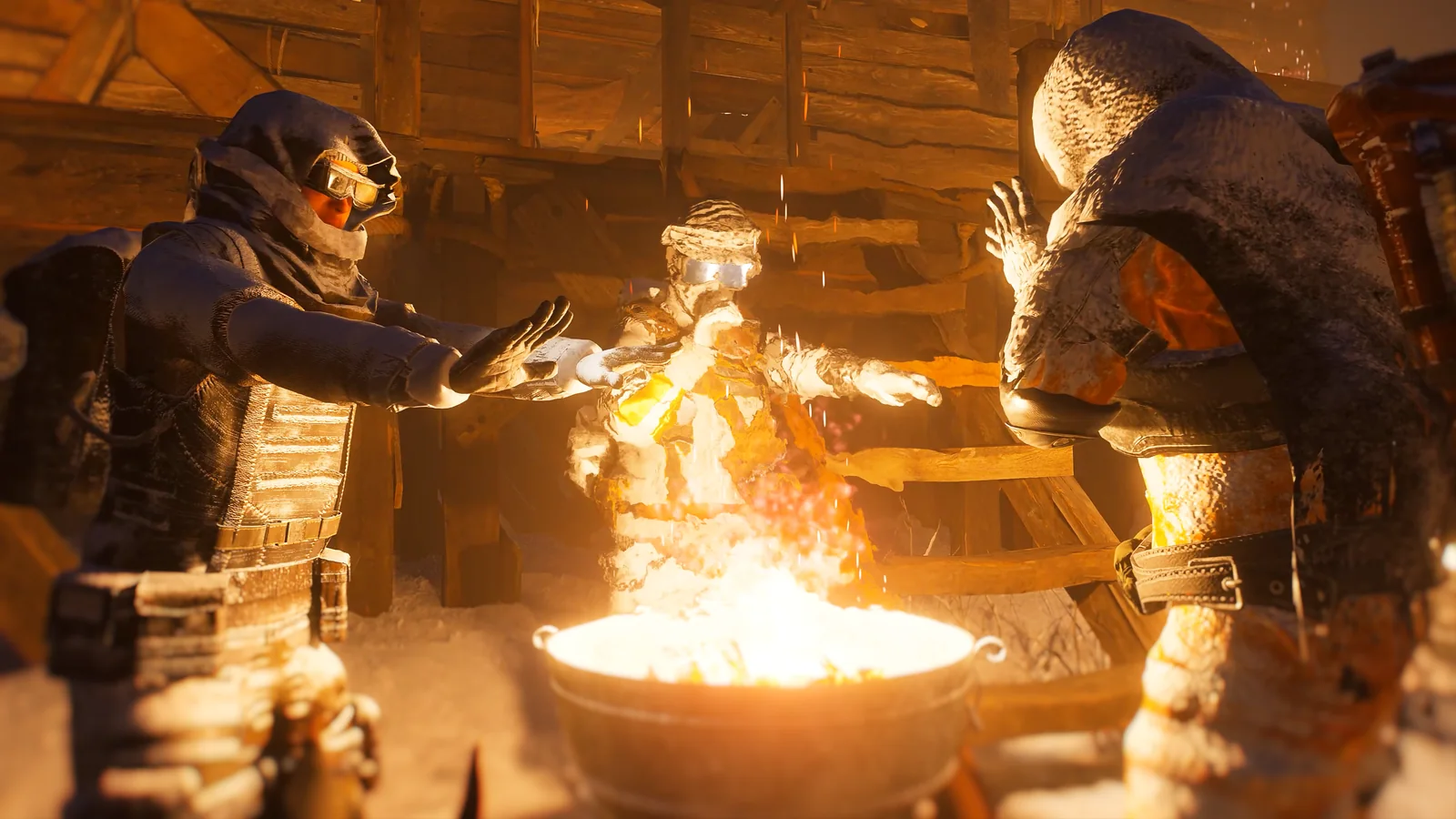 Three bundled survivors warm their hands over a bright fire inside a rough wooden shelter.